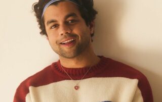 Picture of Akash Nigam, man with short curly hair wearing a red, white and blue stripped sweater
