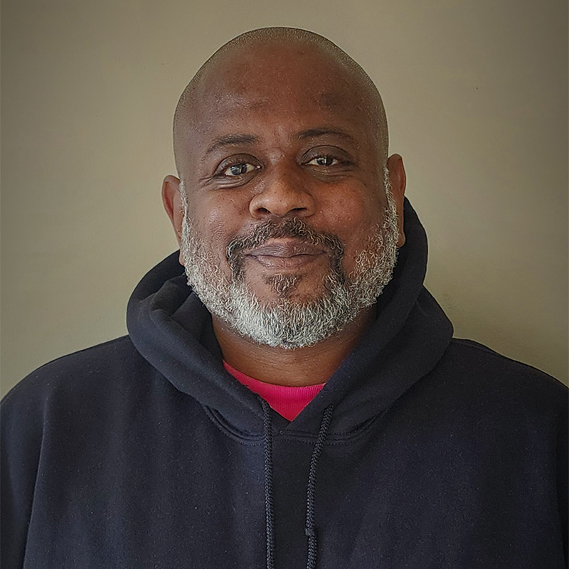 Headshot of a middle-aged bald man with a beard, wearing a black sweatshirt